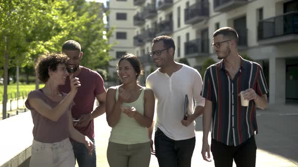 Cheerful Young Woman Showing Smartphone To Her Friends.