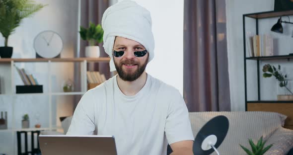 Bearder Looking Into Camera with Collagen Refreshing Eye-Patches and Towel Around His head