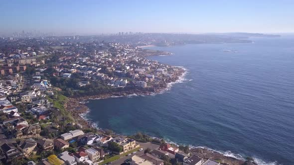 Aerial flight over coastal beachfront coastal property ocean houses with city view in the background