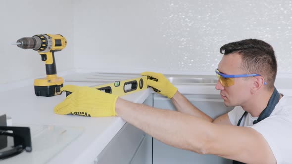 Worker checks the leveling of the working surface of the kitchen table using waterpas