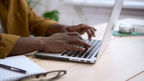 Black Man Working on White Laptop at Desk Against Background of Office at Home Spbas