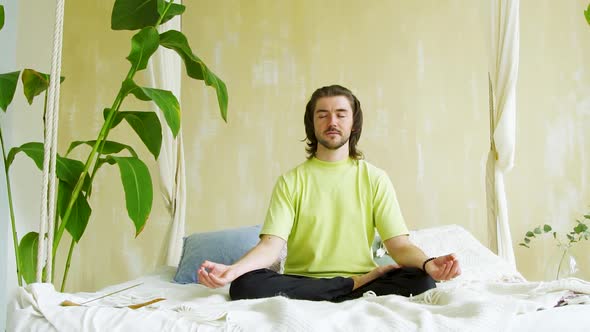 Meditative Man Concetrating Using Yoga and Sitting in Asana in Bed
