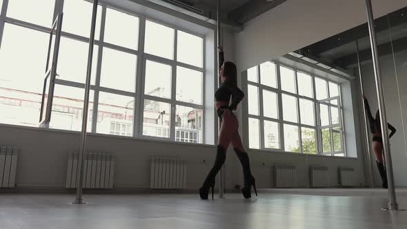 Flexible Woman Dancing on Pole in Studio