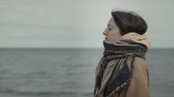 Portrait of woman in warm clothing standing against sea