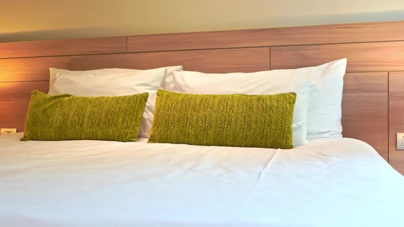 Pan left to right across a bed decorated with green throw pillows.