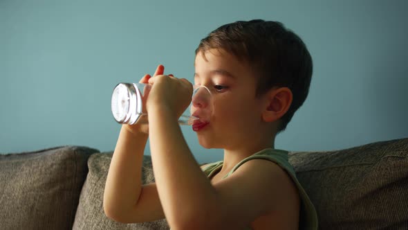 Cute Little Boy Drinking a Glass of Water in Home