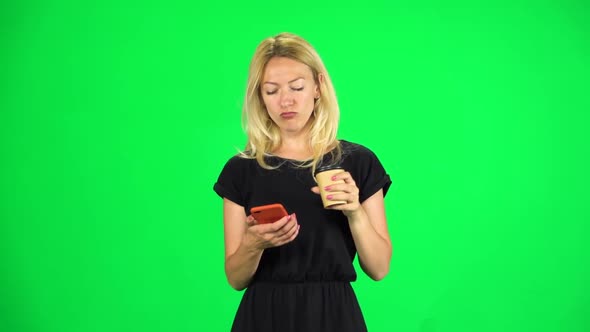 Blonde Girl Goes and Texting with Smartphone While Holding a Paper Cup of Coffee. Chroma Key. Slow