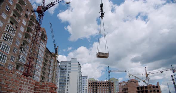 Crane Lifts the Load and Rotate at Building Construction Site, Architecture Apartments. Wide Shot