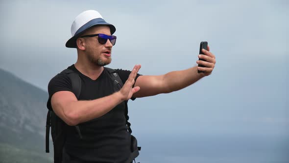 Smiling Male Travel Blogger Backpacker Shooting Video Online Live Air Broadcasting on Top Mountain