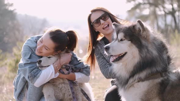 Young Beautiful Women Are Smiling and Hugging with Their Fluffy Cute Dogs