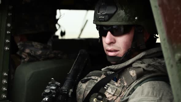 Soldier wearing sunglasses looking out side door of Humvee