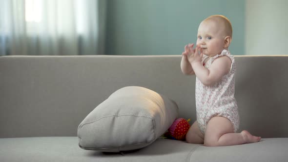 Active Baby Girl Clapping Hands and Playing on Sofa at Home, Happy Childhood