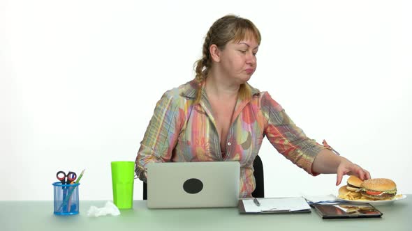 Employee Eating Burger While Working at Notebook