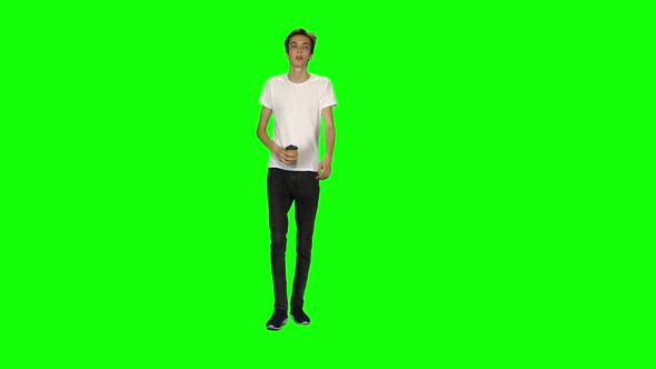 Tall Skinny Teen Guy Calmly Walking and Drinking Coffee on Green Screen Background. Chroma Key, Shot