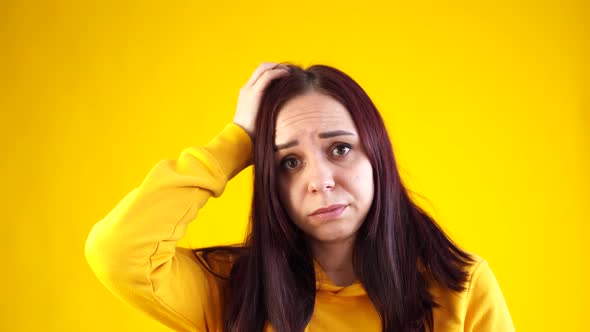 Close Up of Young Woman Scratching Thoughtfully Her Head on Yellow Background