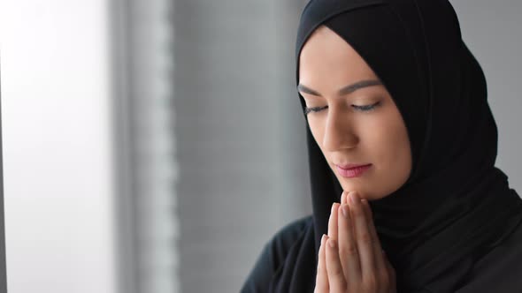 Closeup Muslim Female in Black Hijab Praying Tranquil Face Expression