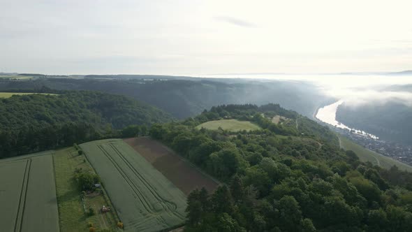 The picturesque river valleys of the Moselle wine region on a sunny and foggy morning. Panning aeria