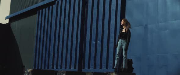 Young woman looks around standing in front of a huge metal container