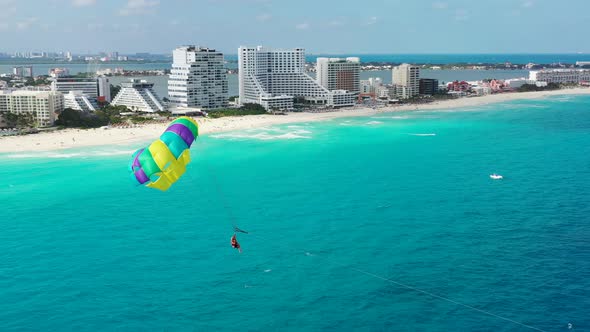 Camera rotates to show parasailer near Cancun's resorts