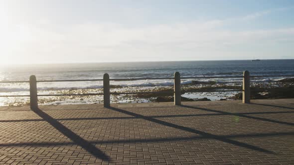 African american woman running on promenade by the sea at sundown