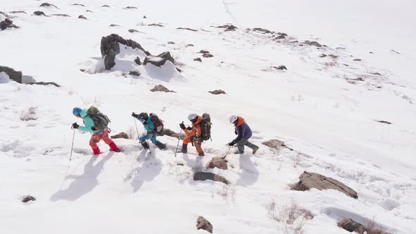 four tourists follow each other through the high snow, helping themselves with ski poles. The last t