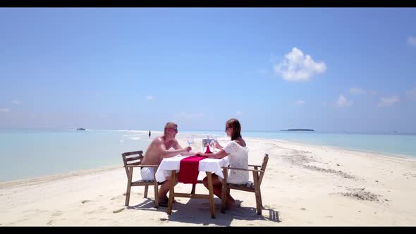 Man and lady tanning on paradise island beach voyage by blue ocean with bright sandy background of t