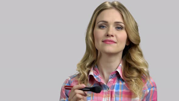 Portrait of Young Blond Woman Doing Makeup Using Brush