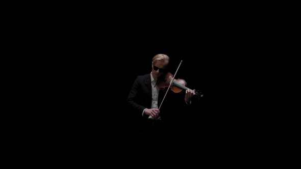 Young Caucasian Male in Black Suit and Glasses Plays Violin on Dark Background