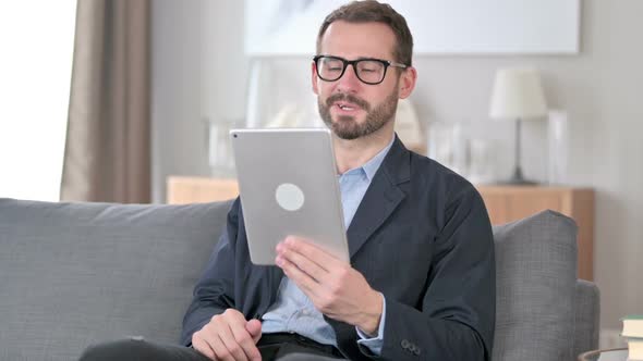Online Video Call on Tablet By Young Businessman at Home