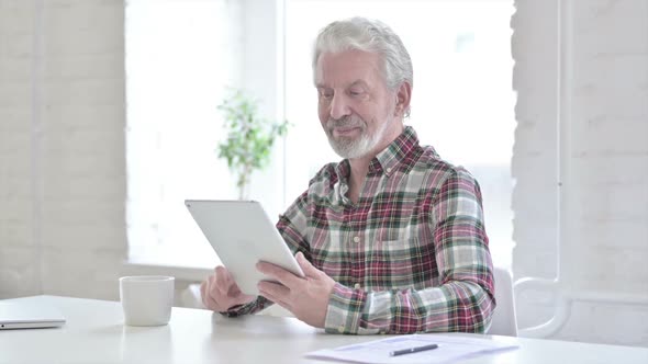 Casual Old Man Doing Video Chat on Tablet in Office