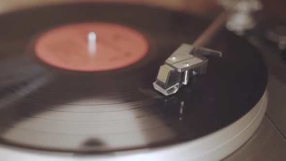 An old dusty record player from the 1970's is playing a black vinyl record with a red label. The cam