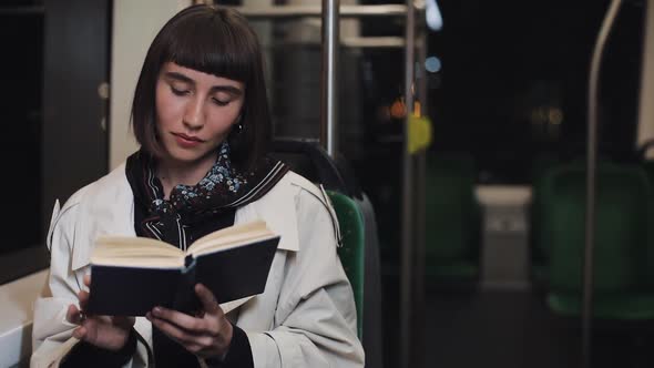 Young Woman or Passenger Reading Book Sitting in Public Transport, Steadicam Shot. Slow Motion. City