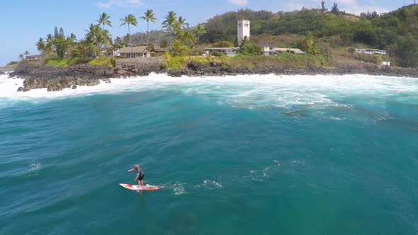 Aerial view of a man sup stand-up paddleboard surfing in Waimea, Hawaii