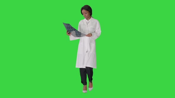 Young African American Female Doctor Looking at Xray While Walking on a Green Screen Chroma Key