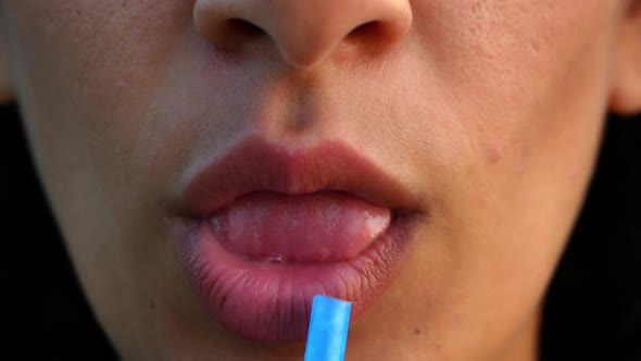 Close-up of female lips drinking a drink from a drinking straw.