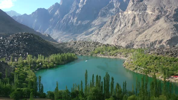 aerial drone of a boat at Upper Kachura Lake in Skardu Pakistan on a sunny summer day surrounded by