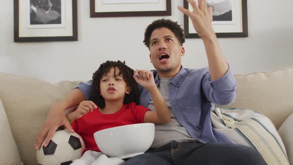 Happy biracial man and his son watching football match together