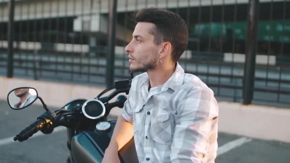 Portrait of Man Biker with Custom Motorcycle on Street at Sunset