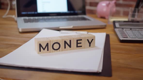 Word money is folded with hands made of wooden cubes with letters on the desktop. Concept of wealth