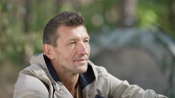 Relaxed Caucasian Man in Sunshine Looking Away Enjoying Calm Leisure in Forest Camp