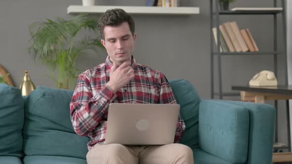 Man with Laptop Thinking on Sofa