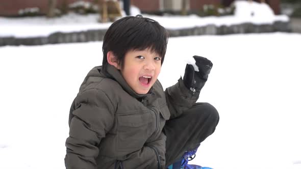 Cute Asian child playing on snow in the park