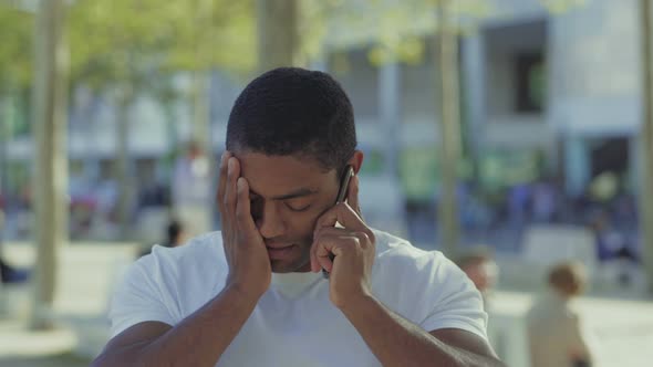 Thoughtful African American Guy Talking on Phone and Rubbing Face