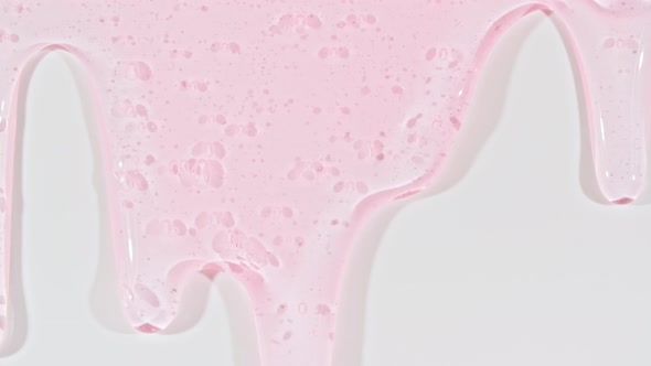 Pink Transparent Cosmetic Gel Fluid With Molecule Bubbles Flowing On The Plain White Surface