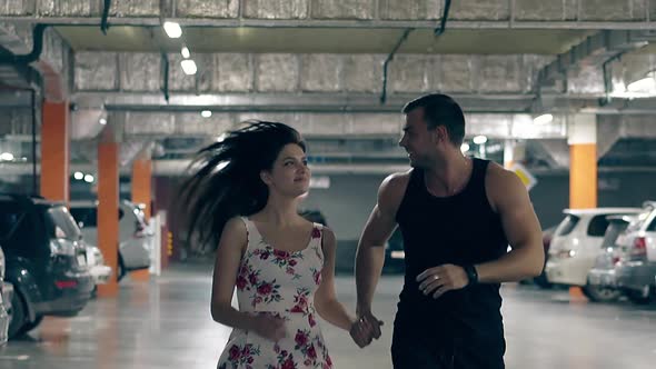 Beautiful Couple Runs on Gray Asphalt Near Orange Columns