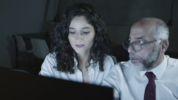 Businessman and Businesswoman Discussing Work in Dark Office