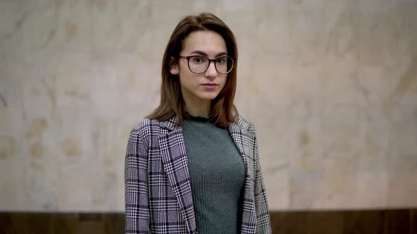 A Young Woman Is Standing in the Subway. In the Background a Train Rides