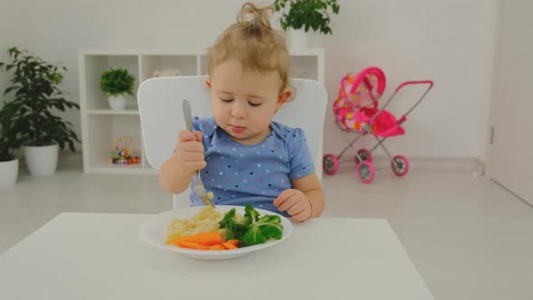 The Child Eats Pasta and Vegetables