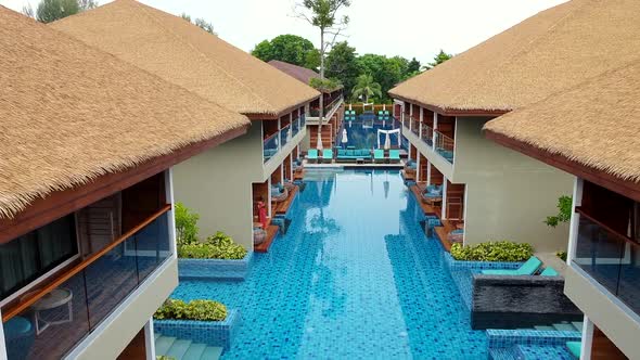 Drone Flying Over Blue Swimming Pools and Modern Houses with Thatched Roofs