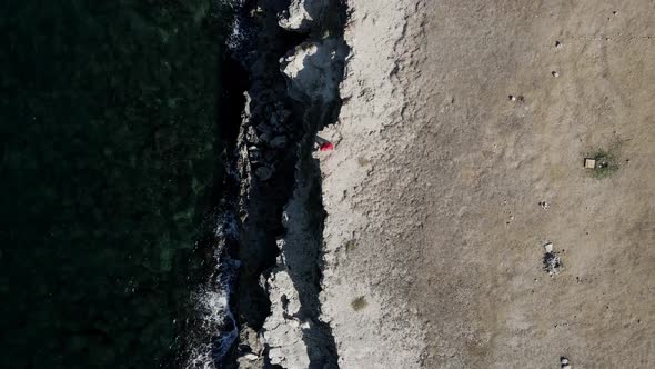 Brunette Woman in a Red Long Dress Walk on the Edge of a Cliff By the Sea